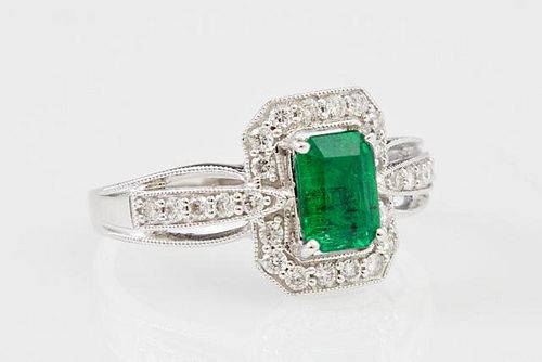 Lady's 18K White Gold Dinner Ring with a .87 carat emerald atop an octagonal border of round diamonds, the pierced shoulders 