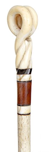 21. Scrimshaw Whalebone Cane- Mid 19th Century- Whale’s tooth handle carved in a double loop, horn-whale’s tooth and wood spacers, 5/8” whale bone sha