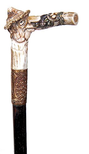 153. Woodsman’s Bird Whistle Cane- Ca. 1930- carved antler handle with a whimsical gentleman with a feathered hat, the extended whistle has a birds ne