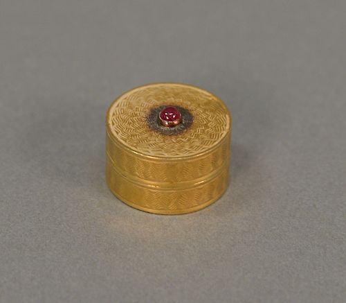 18 karat gold pill box set with red center stone. 10.9 grams ht. 7/16 inch, dia. 3/4 inch.