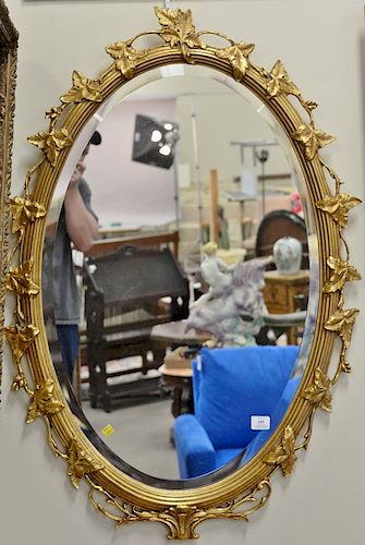 Oval gold framed mirror with carved leaf frame. 44" x 30"