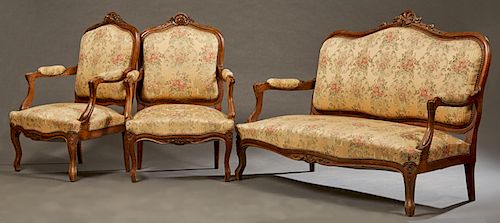 Three Piece French Louis XV Style Carved Walnut Salon Suite, 19th c., consisting of to fauteuils and a settee, with carved foliate crests over shield 
