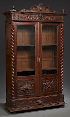 French Henri II Style Carved Oak Bookcase, c. 1880, the arched crest over a stepped crown above setback double doors with glazed upper panels, over re