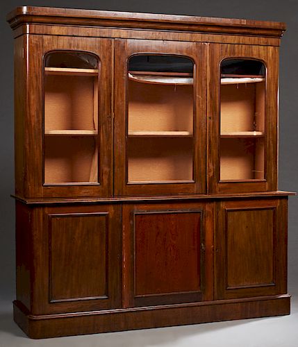 English Victorian Mahogany Three Door Bookcase Cupboard, c. 1870, the stepped rounded corner ogee crown over three arched glazed doors, on a base with