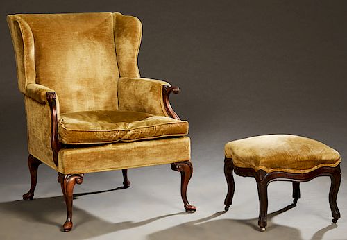 Queen Anne Style Carved Mahogany Wing Chair, early 20th c., the upholstered back over rolled scrolled arms, and a removable cushion on Queen Anne legs