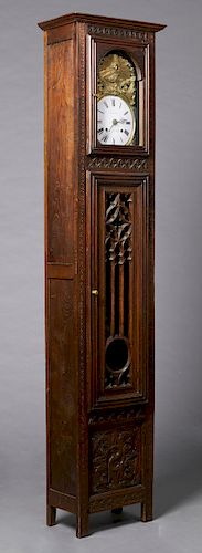 French Gothic Style Carved Oak Tallcase Clock, late 19th c., the stepped crown over a brass repousse face with the Virgin Mary, around an enamel dial 