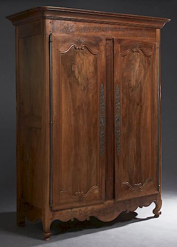 French Louis XV Style Carved Walnut Armoire, c. 1780, the rounded corner stepped ogee crown above two arched panel doors with long steel escutcheons a