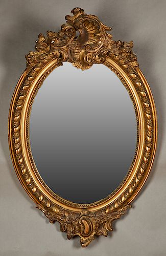 French Louis XVI Style Gilt and Gesso Oval Overmantle Mirror, late 19th c., the elaborate pierced floral crest over a wide frame with swirled bands ar