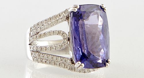 Lady's Platinum Dinner Ring with a cushion cut 13.97 carat tanzanite atop a diamond mounted band with pierced shoudlers, total diamond weight- 1.02 ct