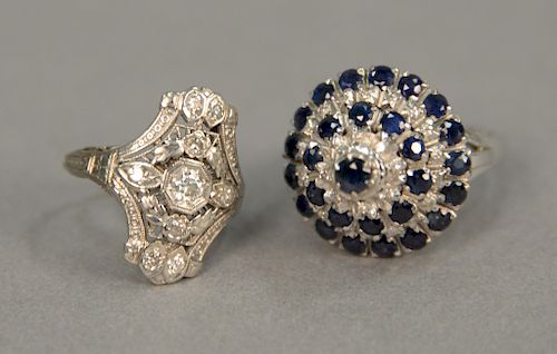 Two 18 karat white gold rings, one filigree with diamonds and one cocktail with diamonds and blue stones, 14.2 grams