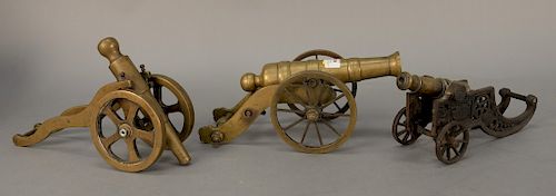 Three early brass signal cannons, one with black painted iron base, one large model with adjustable height on brass wheels, and a sm...