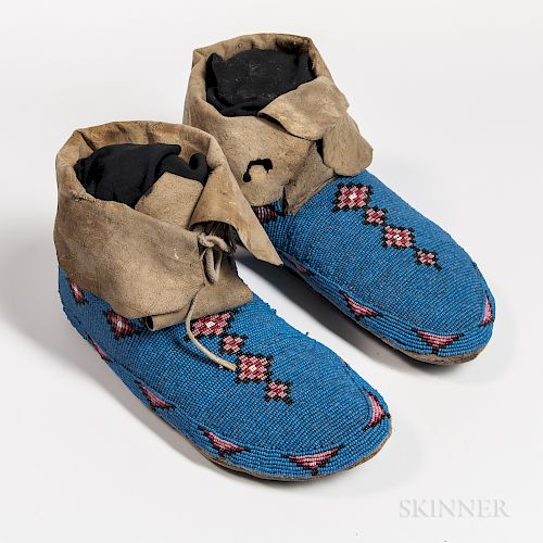 Plains Cree Beaded Hide Moccasins, c. 1880, soft-sole forms beaded with geometric designs on a blue ground and high cuffs, lg. 10 1/2 i