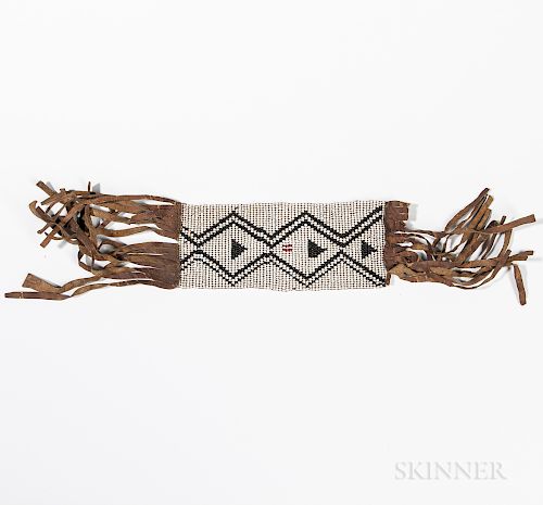 Plains Beaded Hide Armband, c. 1880s, black and red beaded design on white ground, with long hide fringe at either end, lg. 18 1/2, wd.