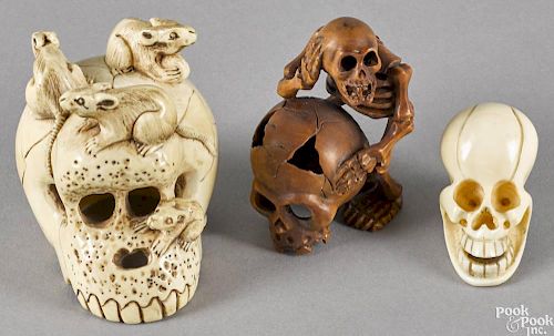 Two Japanese carved ivory skull netsukes, together with a carved boxwood example.