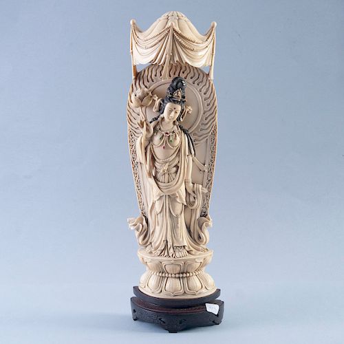 Guan Yin con loto y baldaquino. China, prin. del siglo XX. Talla en marfil, con motivos esgrafiados y simulantes. Con base de madera.