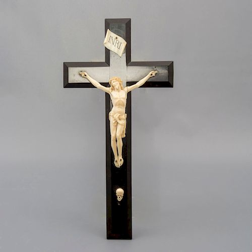 Crucifijo. Siglo XX. En talla de marfil. Con cruz de madera y cartela con inscripción "INRI". Con la representación del craneo de Adán.