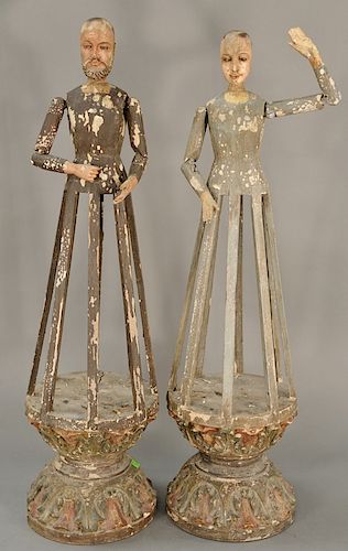 Pair of carved and polychrome cage dolls, 
having painted wooden body and head with glass eyes and jointed arms supported by a caged...