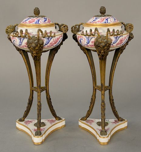 Pair of Sevres covered urns mounted in bronze supports, 
Classical face, legs ending in hoof feet, set on triangular porcelain base ...
