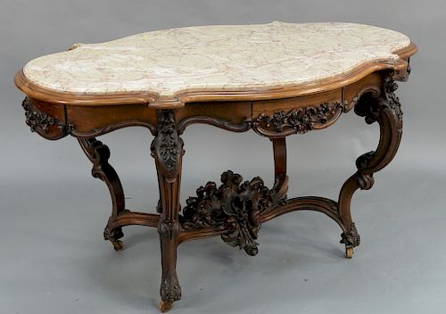 Victorian Rosewood center table with inset shaped marble top,  over conforming frieze with scrolls and roses, and four drawers on sc...