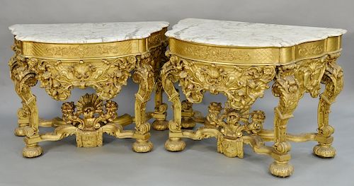 Pair of gilt Louis XIV style console tables with shaped marble tops, over conforming frieze on carved and scrolled legs, set on modified ...