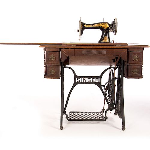 Máquina de coser. Estados Unidos. Siglo XX. Marca Singer. En talla de madera tallada y enchapada. Con soportes de herrería.