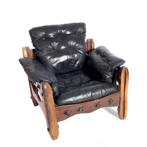 Sillón individual. Siglo XX. Elaborado en madera tropical. Diseño Don S. Shoemaker. Con respaldo y asiento capitonados en piel negra.