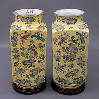 Par de jarrones. China. Elaborados en porcelana. Con base de madera tallada. Decorados con elementos florales sobre fondo amarillo.