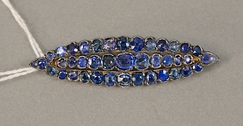 14 karat gold brooch mounted with sterling silver and set with blue stones.