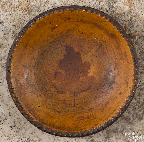 Pennsylvania redware pie plate, early 19th c., with central dark orange glaze of a leaf