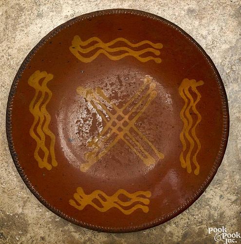 Redware charger, 19th c., with yellow slip X surrounded by wavy lines, 12 1/2'' dia.