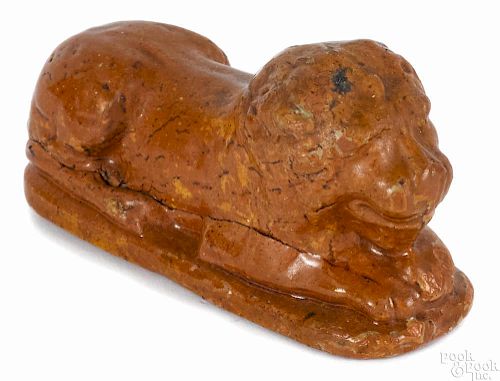 Redware figure of a recumbent lion, late 19th c., 2 1/2'' h., 5'' w. Provenance: R. H. Wood
