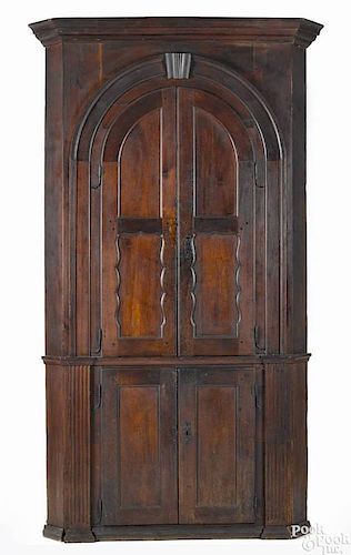 Pennsylvania walnut one-piece corner cupboard, ca. 1770, with a scallop-paneled upper door