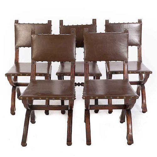 Lote de 5 sillas. SXX. En talla de madera. Con tapicería de piel color marrón. Respaldo cerrado, fustes en "X" y soportes tipo bollo.