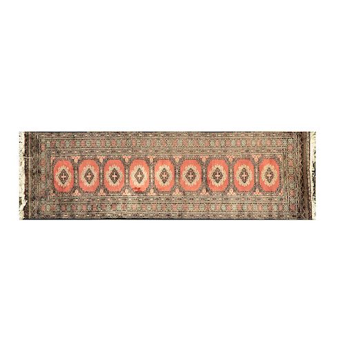 Tapete de pasillo Pakistán, siglo XX. Estilo Bokhara. Anudado a mano en fibras de lana. Con motivos geométricos sobre fondo rojo.