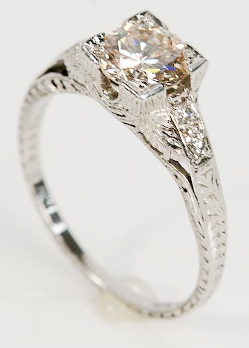 Platinum and diamond engagement ring having center diamond approximately .75 cts. flanked by 2 small diamonds on either side in carv...