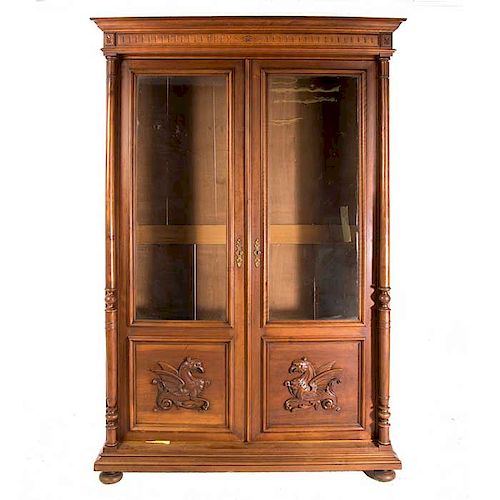 Librero. Francia. Siglo XX. Estilo Enrique II. En madera tallada de nogal. Con 2 puertas de cristal y fustes compuestos.