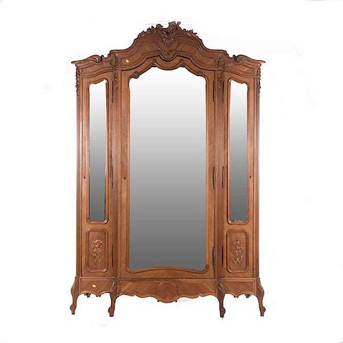 Armario. Francia. Siglo XX. Estilo Luis XV. En talla de madera de nogal. Con 3 puertas con espejo de luna irregular biselada.