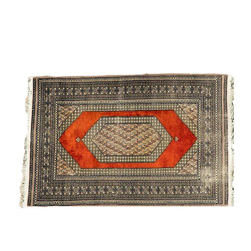 Tapete. Siglo XX. Estilo Bokahara. Elaborado en fibras de lana y algodón. Decorado con motivos geométricos y medallón central.
