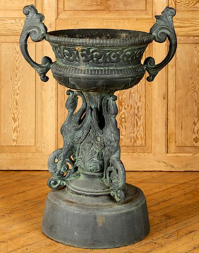 A CAST IRON URN WITH HERON SUPPORTS