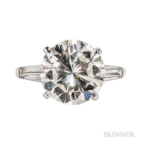 Platinum and Diamond Solitaire, prong-set with a round brilliant-cut diamond weighing 5.81 cts., flanked by tapered baguettes, size 5 3