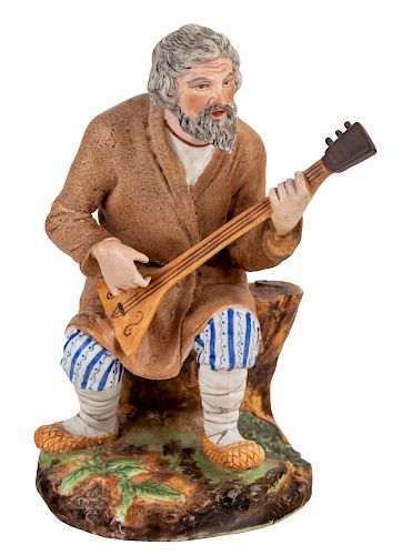A RUSSIAN PORCELAIN FIGURE OF A SEATED BALALAIKA PLAYER, POPOV PORCELAIN FACTORY, MID-19TH CENTURY