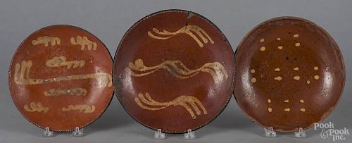 Three Pennsylvania slip decorated redware plates, 19th c., 8'' dia., 8 3/4'' dia., and 9 1/4'' dia.