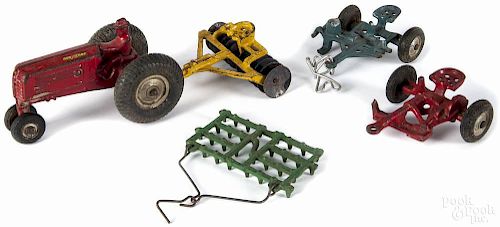 Arcade cast iron tractor, mid 20th c., with four implements, 5'' l.