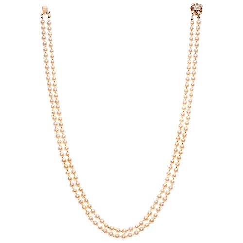 A cultured pearl necklace with a pearl and sapphire 14K yellow gold clasp.
