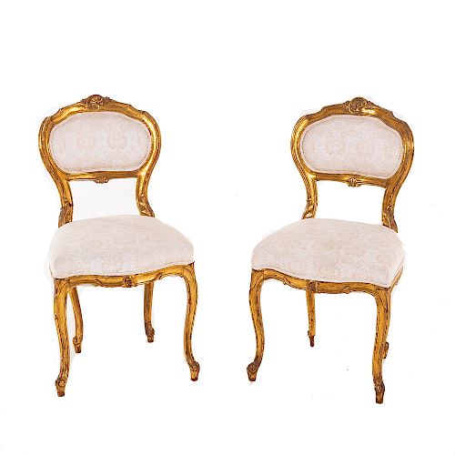 Par de sillas. Siglo XX. En talla de madera. Con respaldos semiabiertos y asientos en tapicería color beige, fustes semicurvos.