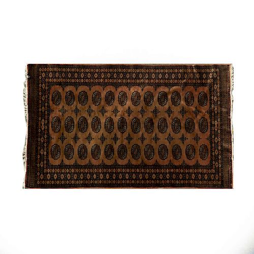 Tapete. Pakistán, siglo XX. Elaborado en fibras de lana y algodón. Decorado con motivos geométricos sobre fondo café.