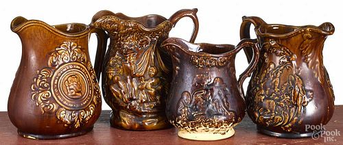 Four Rockingham type pitchers, ca. 1900, with relief decoration, tallest - 8''.