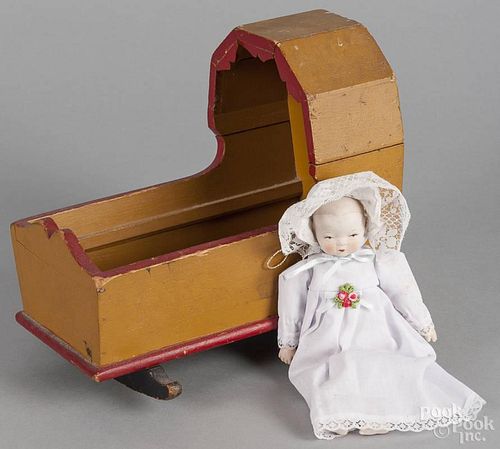 Painted pine doll cradle, ca. 1900, retaining a mustard and red surface, 8 1/2'' h.