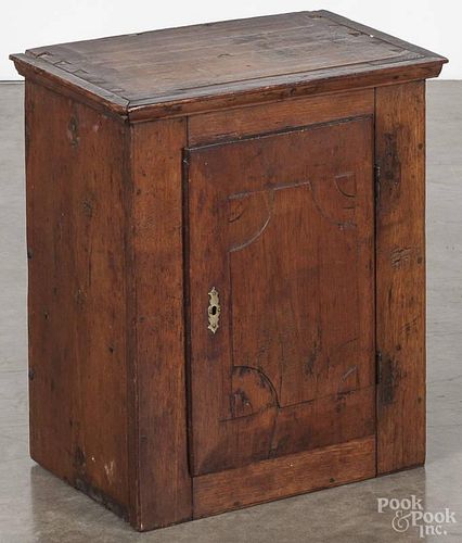 Pennsylvania walnut hanging cupboard, late 18th c., with a carved raised panel door, 20'' h.
