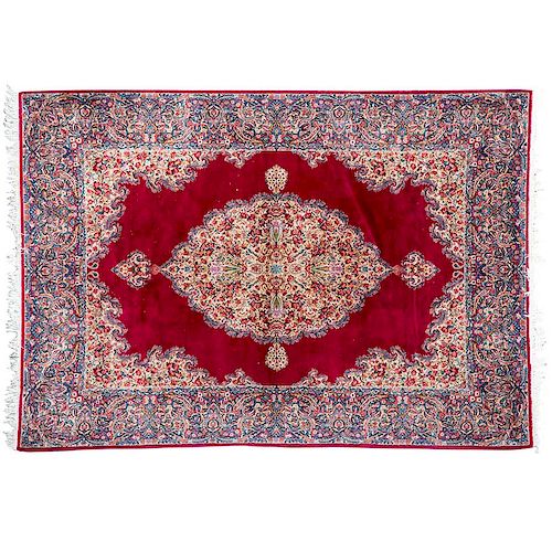 Tapete. Persia, siglo XX. Estilo Ghom. Anudado a mano en fibras de lana y algodón. Decorada con motivos florales y orgánicos.
